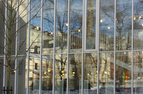 Puiden heijastuksia puiston lähellä olevan rakennuksen ikkunajulkisivussa